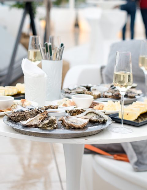 Opened oysters and lemon with white wine on the table. Restaurant delicacy, beautiful table setting. Saltwater oysters dish. Romantic dinner in restaurant